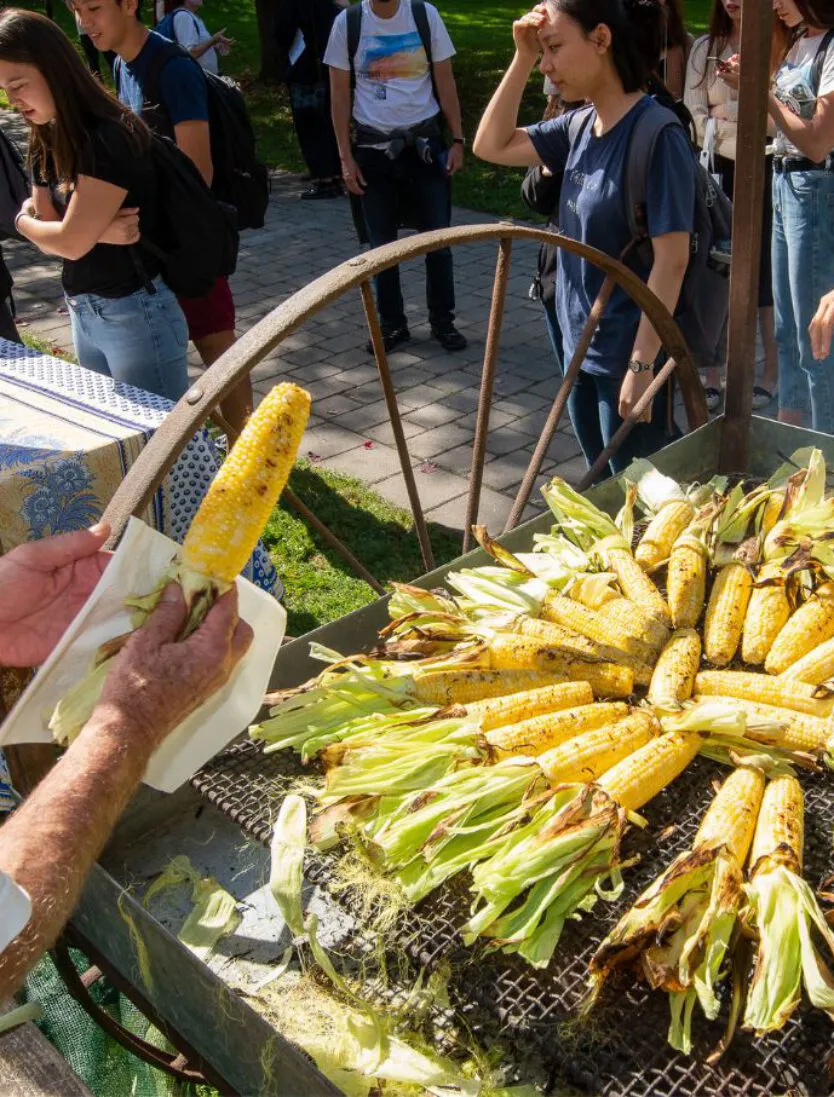 a man serves freshly roasted corn to a crowd of community members