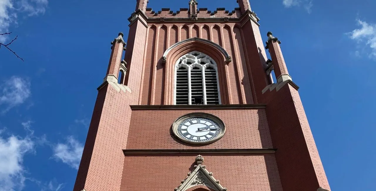 an image of the exterior of a cathedral, captured from below. A blue sky with some clouds appears in the background.