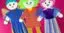 Three vibrant dolls are adorned with paper clothing. Additional details and texture are created with glitter, tape, feathers and pleats.