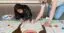 a school-aged child draws a larger than life character alongside an art instructor